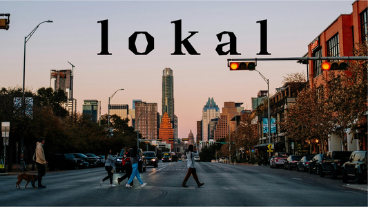 Downtown Austin at sunset, with people crossing a crosswalk surrounded by vibrant city life. The Lokal logo is subtly overlaid, blending seamlessly into the warm, golden hues of the scene.